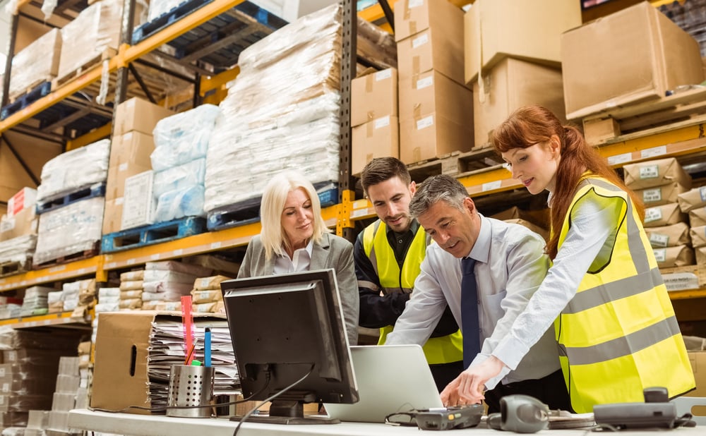 Warehouse managers and worker talking in a large warehouse using their ERP solution